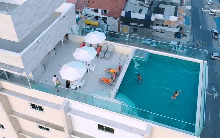 Foto com vista aérea da piscina do ultimo andar e avenida no fundo no verano pajuçara by tropicalis