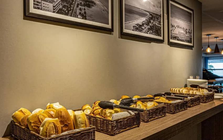 Foto de uma bancada com várias cestas de pães variados no Happy Hotel Manaíra