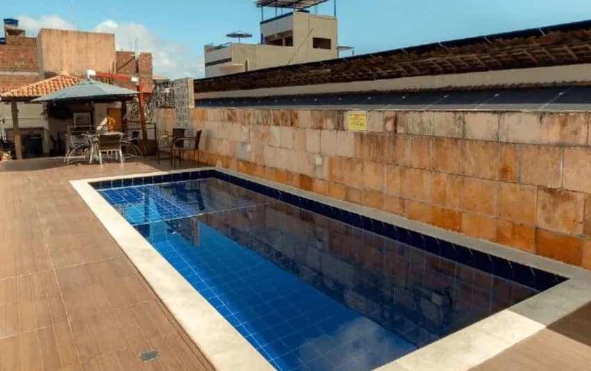 Foto de piscina retangular em área externa, com mesas ao fundo no Happy Hotel Brisa do Mar